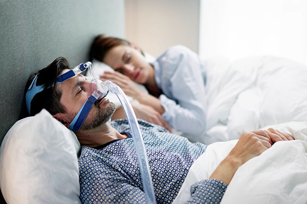 man with sleeping mask on for sleep apnea